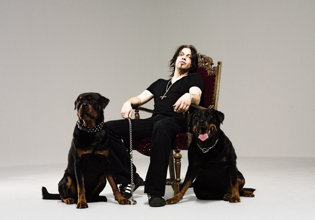 Leif Edling of Candlemass in an official promo photo for Death Magic Doom (2009), sitting on a throne with two Rottweilers during the Nuclear Blast promo shoot.